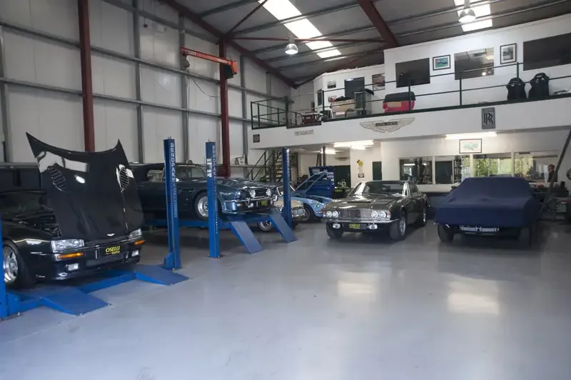 The Oselli workshop: classic and modern cars on two-post lifts under strip lights