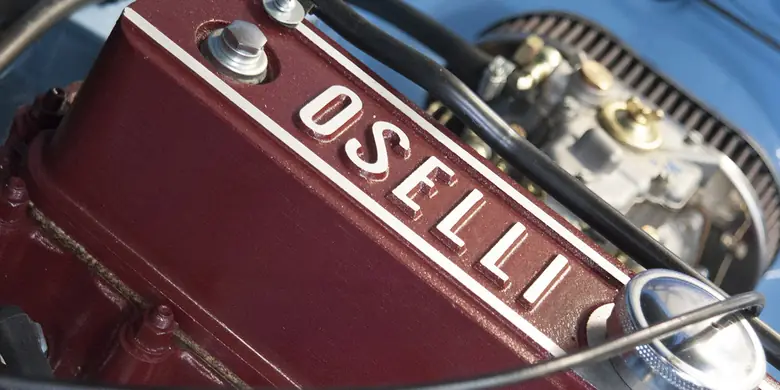 An Oselli rocker cover, painted red with the name cast in raised letters, in the engine bay of a classic car